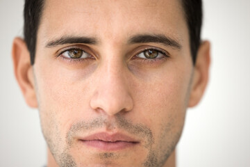 Obraz premium Natural masculine beauty. Close up cropped portrait handsome young male face with brown eyes stylish stubble looking at camera with calm serious expression. Facial skin care self confidence concept
