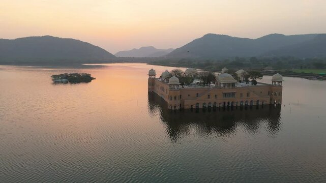Aerial drone shot revealing the contrast between Jal Mahal&rsquo;s warm tones and the blue water around it.