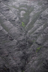 A stream flows down scorched hillsides after forest fires