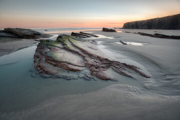 Low tide leaves behind muddy rocks and crystal clear pools