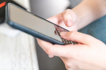Young female hands with black smarphone watching screen. Digital device addiction, social and education.Close up of hands holding smartphone