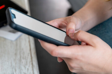 Young female hans with black smarphone watching screen. Digital device addiction, social and education.Close up of hands holding smartphone