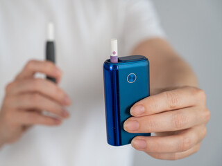 Fototapeta premium A woman compares two different tobacco heating systems. Electronic cigarette.