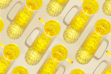 Yellow glowing glass cups on beige background, casting artistic light reflections and shadows in...