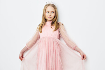 Young girl in a pink tulle dress posing elegantly with a crown, showcasing innocence and charm...