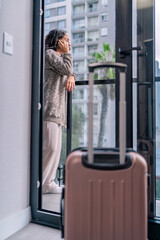 Fototapeta premium Digital nomad making a phone call on balcony of airbnb apartment