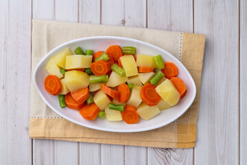 Cooked vegetables in a plate over wooden table