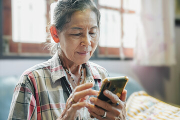 An elderly woman engages with her smartphone, highlighting technology's role in modern daily life.