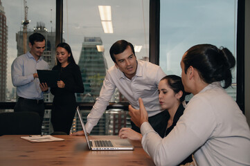 Team collaboration in a modern office discussing strategies surrounding a laptop and presentation.