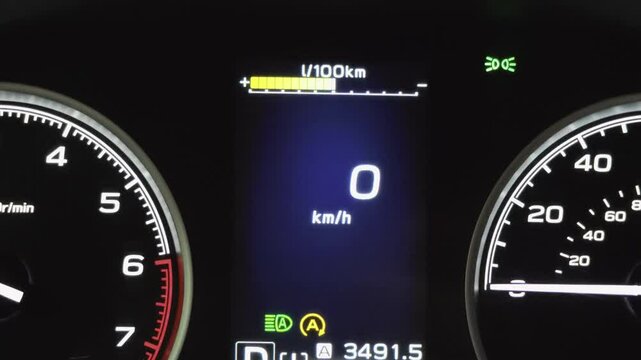 Closeup of a digital car dashboard displaying zero kilometers per hour and different light indicators
