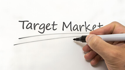 A hand underlines the words target market written on a whiteboard with a black marker