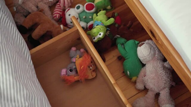Child puts up her toys away in an under bed storage box.