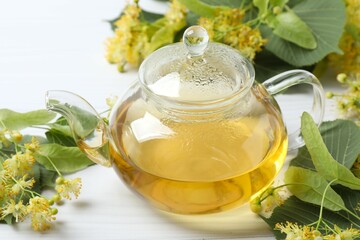 Green tea with fragrant linden in teapot on white background