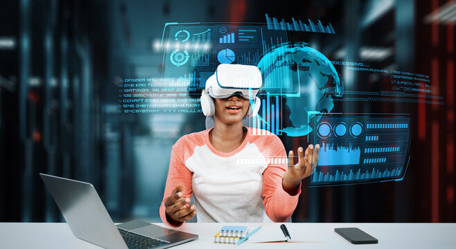 Girl using laptop and augmented glasses connecting metaverse while doing homework at table with book and laptop. Student looking at holographic and using artificial intelligence working. Ingenuity. - Powered by Adobe