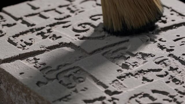 Archaeologist removing dust from ancient stone tablet with brush