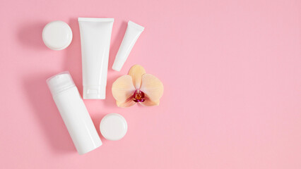 Set of cosmetic products white bottles and containers laid out on pastel pink background and...
