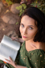 Portrait of beautiful short haired woman sitting on ground with book in hands