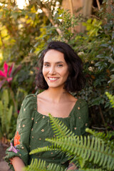 Portrait of brunette woman with short hair in front of plants and trees