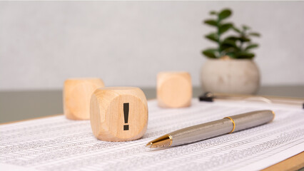 Wooden cube with exclamation mark on financial document
