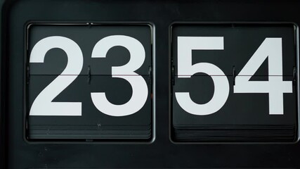 Closeup retro flip clock with white numbers on black background. Macro flipclock