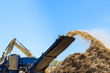 Large equipment converts organic waste into mulch at busy construction site on land clearing for...
