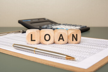 wooden blocks spelling LOAN on finance sheet