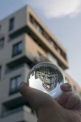 hand holding a glass ball with apartment complex on the background