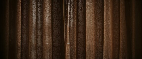 Closed brown fabric curtains with soft light filtering through in a dimly lit interior setting