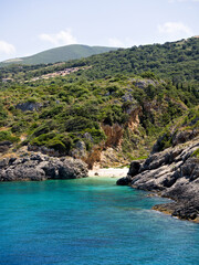Fototapeta premium Small turquoise bay on Zakynthos island, framed by dramatic rocky coastline and lush green cliffs.