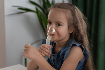 Caucasian young girl using nebulizer machine for breathing treatment at home. Nebulizer use for...