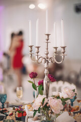 Elegant table centerpiece featuring a silver candelabra and fresh flowers at a festive indoor celebration during twilight hours