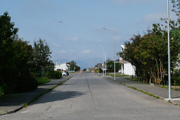 Naklejka premium Quiet street scene with green surroundings and distant mountain view in Akranes, Iceland