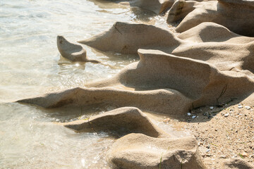 Beautiful eroded stone on calm sea waters on sunny summer day on the beach closeup