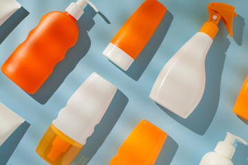 Skincare bottles and sprays of vibrant orange and white displayed on blue for summer vibes