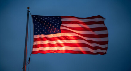 An iconic American flag waving majestically against a deep blue evening sky, illuminated from below, symbolizing patriotism, freedom, and national pride. Ideal for US national holidays, remembrance