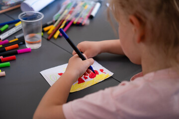 Children draw on the poster with pencils and paints
