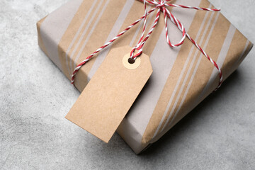 Kraft paper wrapped gift box tied with red and white twine, featuring a blank kraft tag on a light...