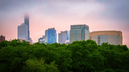 Obraz premium Brooklyn downtown skyline and buildings in New York City, viewed from the Brooklyn Bridge at a foggy summer sunset after rain over the East River in USA