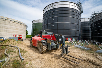 Neubau einer modernen Biogasanlage,  Teleskoplader zwischen Hochbehältern aus Beton.