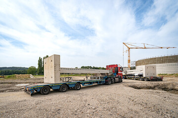 Betonbau - Beton-Fertigteile für Hallenbau werden mit LKW angeliefert und aufgestellt, Symbolfoto.