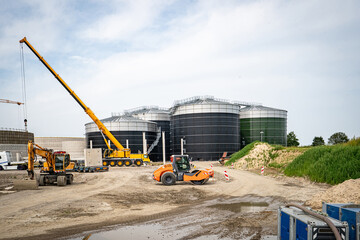 Aufstellen von großen Betonteilen mit einem Baukran für den Bau einer Industriehalle und Biogasanlage.
