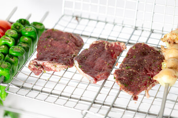 Raw seasoned lamb chunks, ready for grilling, white background.