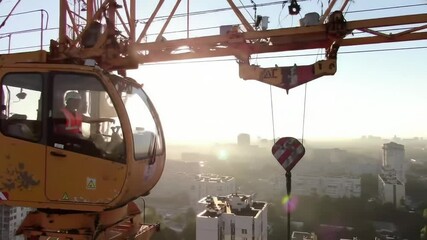 Man, a crane operator, working in an industrial cabin high above the city, operating heavy machinery at a construction site footage. - Powered by Adobe