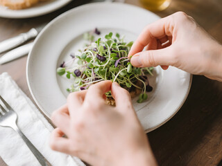 Culinary Hands Adding Microgreens to a Healthy Plate
