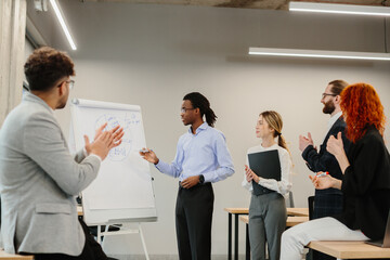 Young businessman explaining strategy to colleagues applauding him