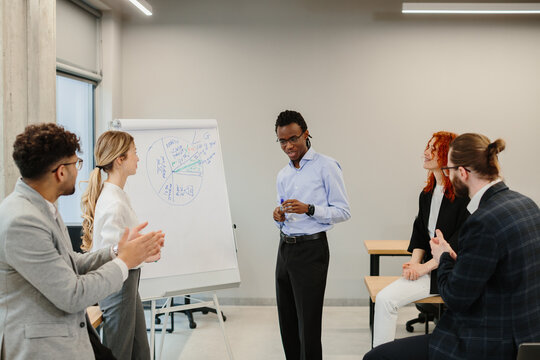 Business team analyzing charts on flip chart during presentation in office