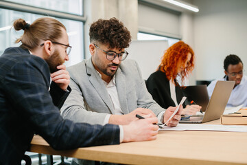 Business people working together in modern office analyzing documents and using laptop