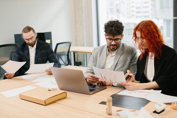 Business people working together analyzing financial chart at office desk