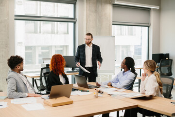 Businessman leading meeting with diverse team in modern office