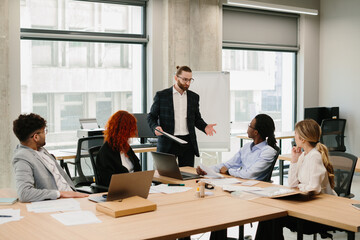 Businessman leading a presentation to diverse team in modern office